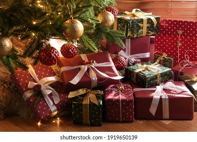 Pile of gift boxes near Christmas tree on floor