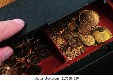 A Pile Of Gold Coins In An Open Cash Box