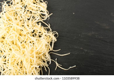 Pile Of Grated Cheese On Black Background. The Photo From Above