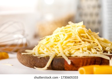 Pile of grated cheese on a cutting board close-up. Cooking pasta with grated cheese. Cheese and kitchen utensils on the table. - Powered by Shutterstock