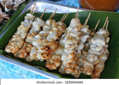 Pile of grilled squid eggs stick on the banana leaf. Famous street food snack in Thai floating market. 