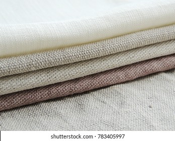 Pile of handmade dull-colored waffle linen cotton napkins towels on white linen background. Different colors. Food photo props. Natural waffle linen cotton fabric. 