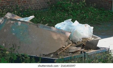 Pile of Hazardous Construction Materials Waste In Large Metal Industrial Garbage Dump Container Bin