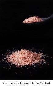 A Pile Of Himalayan Salt And On Top Of It, A Black Spoon With Salt. All On Black Background