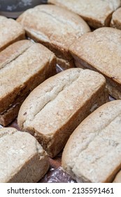 Pile Of Loaf Toast Bread Freshly Baked On Table At The Kitchen. Many Traditional Fresh Round And Square Bread Loaves For Sale. No People. Selective Focus.