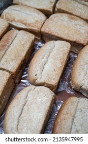 Pile Of Loaf Toast Bread Freshly Baked On Table At The Kitchen. Many Traditional Fresh Round And Square Bread Loaves For Sale. No People. Selective Focus.