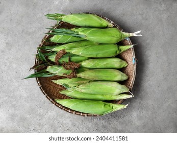 A Pile of Maize or Sweet Corn (Zea Mays) on A Woven Bamboo Tray in the Cement Texture Background