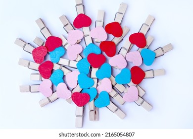 Pile Of Many Colorful Wooden Clothes Pins In Red Heart Shape Patterns On White Background Top View 