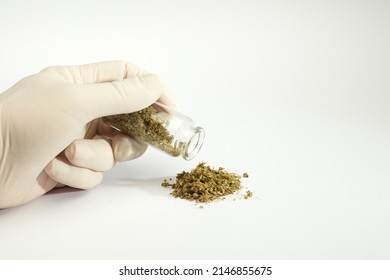 pile of marijuana, gloved hands and glass pot, white background