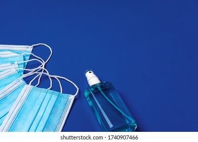 Pile Of Medical Face Masks With Hand Sanitizer On Blue Background