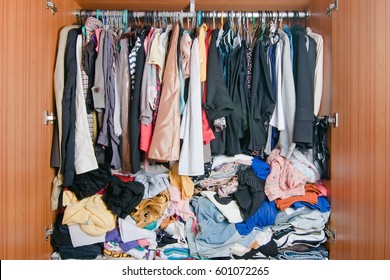 Pile of messy clothes in closet. Untidy cluttered woman wardrobe.