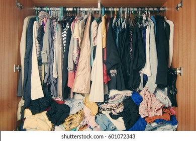 Pile of messy clothes in closet. Untidy cluttered woman wardrobe.