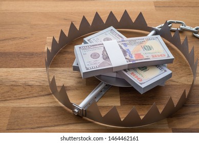 Pile of money dollar banknotes in trap on wooden table background. Concept of financial risk management, loss in stock market, money investment or personal loan.