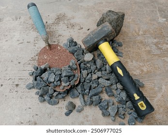 Pile of Mountain's stone crushed with a old cement spoon and sledgehammer lying on it - Powered by Shutterstock