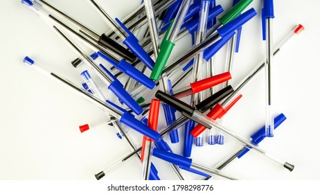 Pile of a lot multi colored plastic ballpoint pens on white background. Abstract stationery background. Top view. Close-up. Many objects.