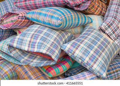Pile of new pillows with scotch pattern pillow cases unarranged for sale in an outdoor market