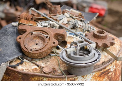 A Pile Of Old Broken Machinery, Spare Parts And Rusty Pieces Of Iron Lying On A Rusty Barrel