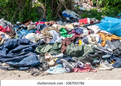 Pile Of Old Clothes And Shoes Dumped On The Grass As Junk And Garbage, Littering And Polluting The Environment