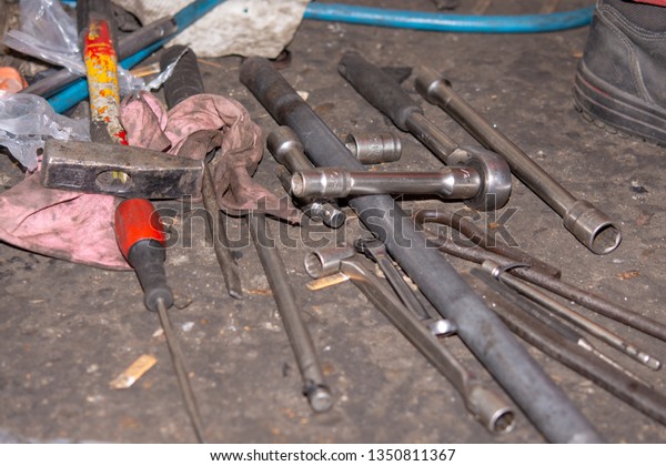 Pile of old and dirty tools in\
the car mechanic workshop. Screwdrivers and wrench on the\
floor