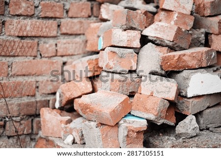 A pile of old red bricks with traces of mortar stacked outdoors.