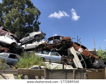 A pile of old rusty cars in a junkyard on a sunny day