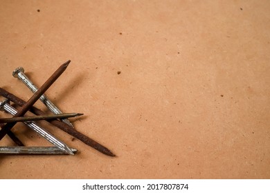 a pile of old rusty nail with brown wood background