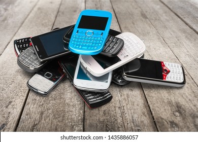 Pile Of Old Smartphones On Wooden Background