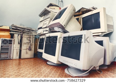 pile of old unused computers and vintage CRT monitors
