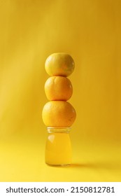 Pile Of Orange Fruits On Orange Juice Jar Isolated On Yellow Background. Fresh And Healthy Drink Concept. 