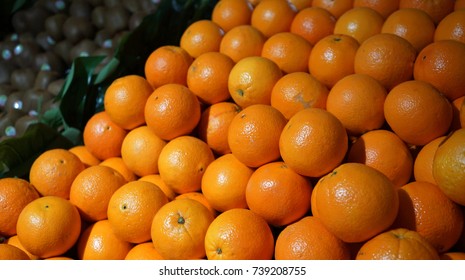 Pile Of Oranges On The Counter In Supermarket, Green Kiwifruit In Background