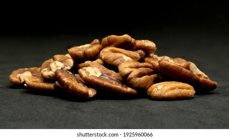 A pile of organic pecan nuts on a dark background