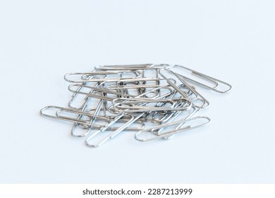Pile paper clip on white background. Is device used to collect small number of documents together temporarily by inserting without damaging paper or document. Wire plated with nickel, and not rust. - Shutterstock ID 2287213999