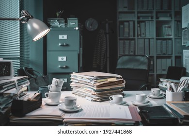 Pile of paperwork and coffee cups on the office desk: deadlines and stressful job concept