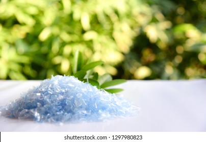 A Pile Of PET Bottle Flakes With Green Tree Blur Background
