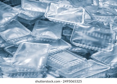 A pile of plastic containers on a blue background ready for packaging food products. All containers are of different sizes and shapes. Industrial food packaging concept background