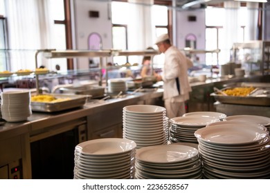 A pile of plates infront of Staff worker preparing food for students in school canteen. Lunch break. Education people and students school cafeteria. Belgrade, Serbia 17.05.2022
 - Shutterstock ID 2236528567