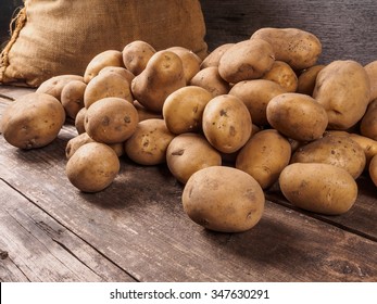 Pile of potatoes lying on wooden boards with a potato bag in the background 