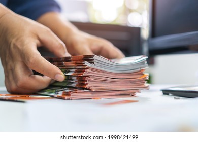 Pile of presentation brochure document concept : Businessman hands working in business Documents on Stacks Brochures papers files for checking achieves reports on busy work computer desk office