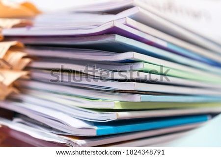 Pile of publication books or documents report papers waiting be managed on desk in busy office. Concept of workload in business finacial paperwork
