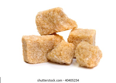 Pile Of Raw Brown Cane Sugar Isolated On White. Focus On Top Cube