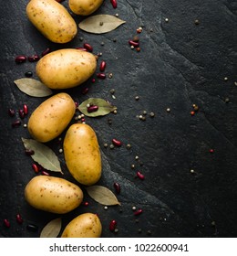 A Pile Of Raw Potatoes On A Dark Stone Background. Preparation Of Soup Or Potato Dishes. Copy Space.