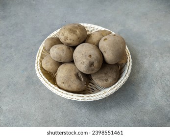 A Pile of Raw Potatoes (Solanum Tuberosum) on A Wicker Basket Isolated in the Cement Texture Background