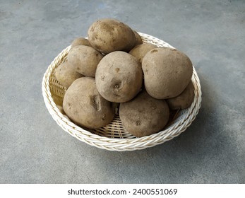 A Pile of Raw Potatoes (Solanum Tuberosum) on A Wicker Basket Isolated in the Cement Texture Background