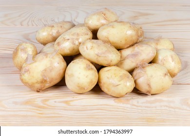 Pile of the raw washed yellow young potatoes with unpeeled thin skin on the rustic table - Shutterstock ID 1794363997