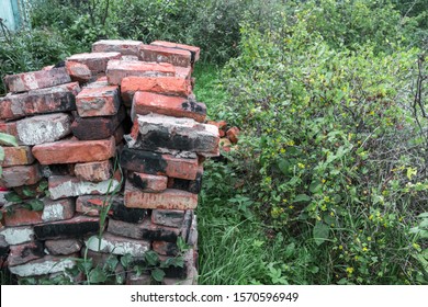 Pile Of Red Bricks After Dismantling And Destruction Building. Conservation Of Old Dirty Burnt Broken Building Blocks With Cracks, Bits Of Plaster And Cement.