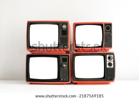 Pile of red old retro television cut out blank screen on white wall background, front view