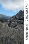 Pile of rocks under the foot of Mount Batur. The clouds above drift peacefully, masking the violent history buried in these blackened rocks, Kintamani, Batur, Bali, Indonesia.