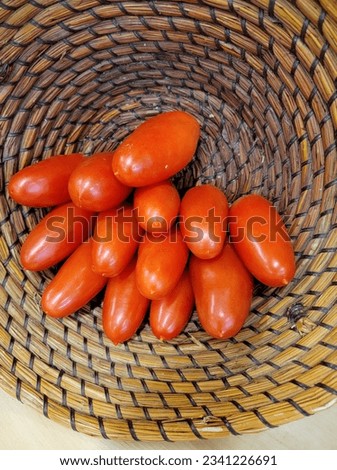 a pile of Roma tomatoes stacked up in a whicker basket that I'd on its side