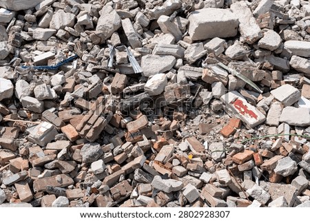 pile of rubble containing broken red bricks and fragmented concrete blocks from a destroyed building