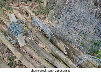 Pile Of Rusting And Broken Farm Fencing Equipment With Grass And Weeds